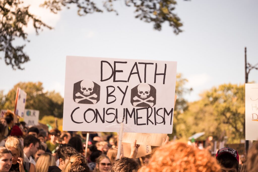 Image of protesters holding up a banner reading 'Death by consumerism'