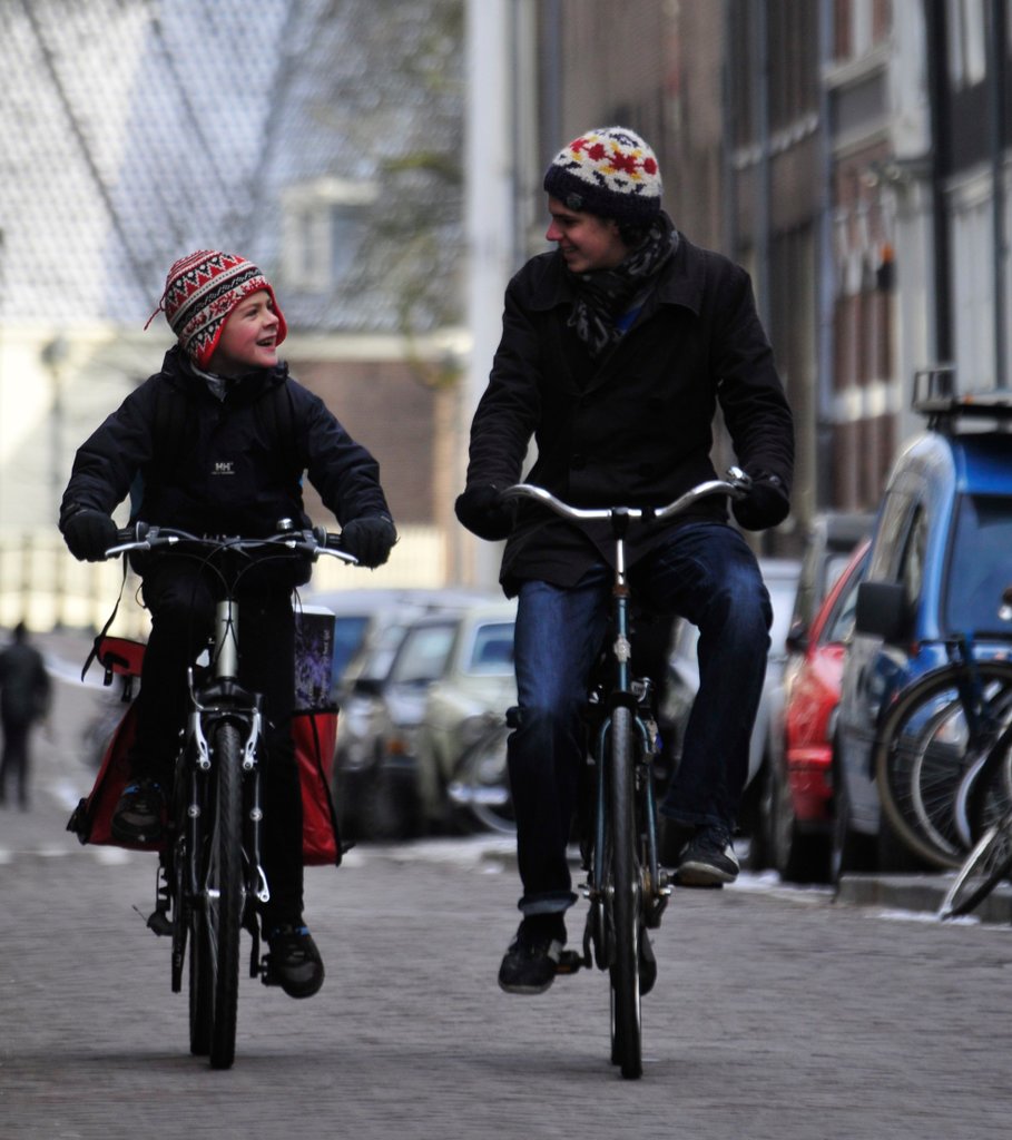 Two brothers cycling. Cycling happens year-round in Amsterdam, which has good infrastructure and relationships between cyclists and motorists.